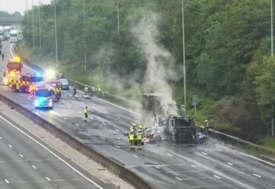 Emergency services at the scene of a large vehicle fire on a multi-lane highway.