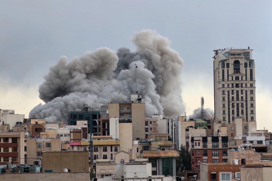 A plume of smoke rises above buildings in Tehran, Iran.