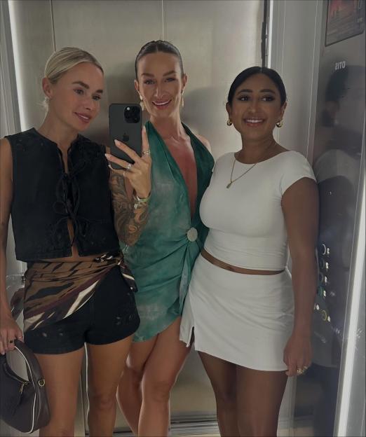 A blonde woman, a woman in a green dress, and a woman in white taking a selfie.