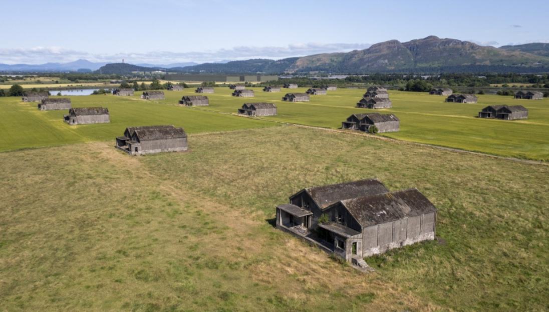 Aerial view of a World War I naval bomb depot, showing many dispersed concrete structures in green fields.
