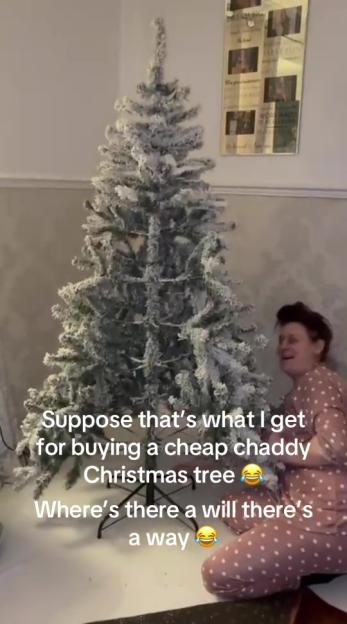 A woman in pajamas laughs next to a flocked Christmas tree with visible gaps, text says "Guess that's what I get for buying a cheap Christmas tree, Where there's a will there's a way."