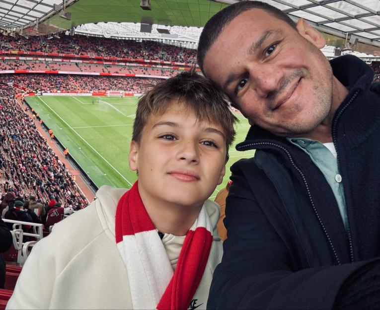 A man and a boy taking a selfie at a football match.