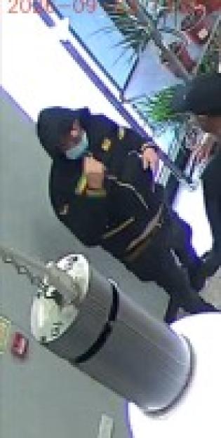 A person in a black hoodie and light blue face mask.