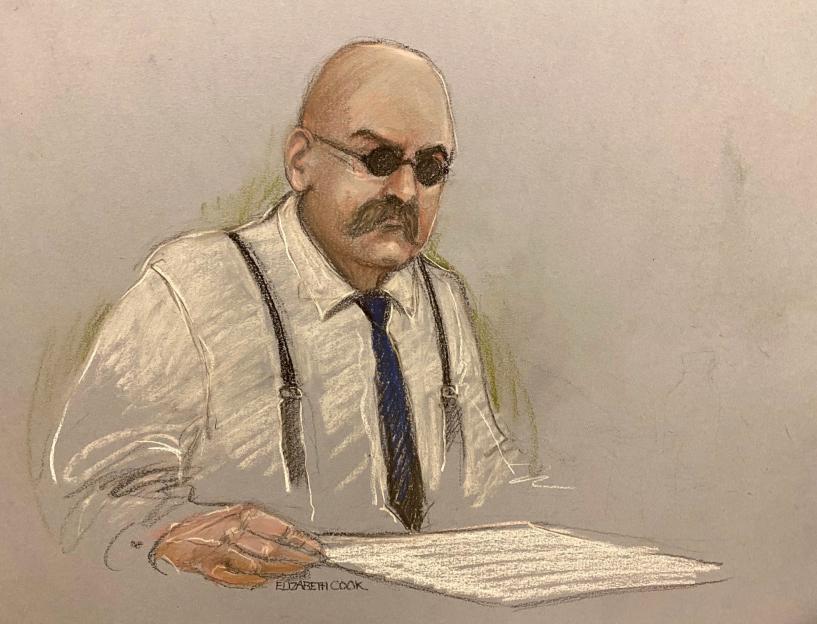 Illustration of Charles Bronson in prison during his public parole hearing, wearing sunglasses, a shirt with suspenders, and a tie, looking down at a document.