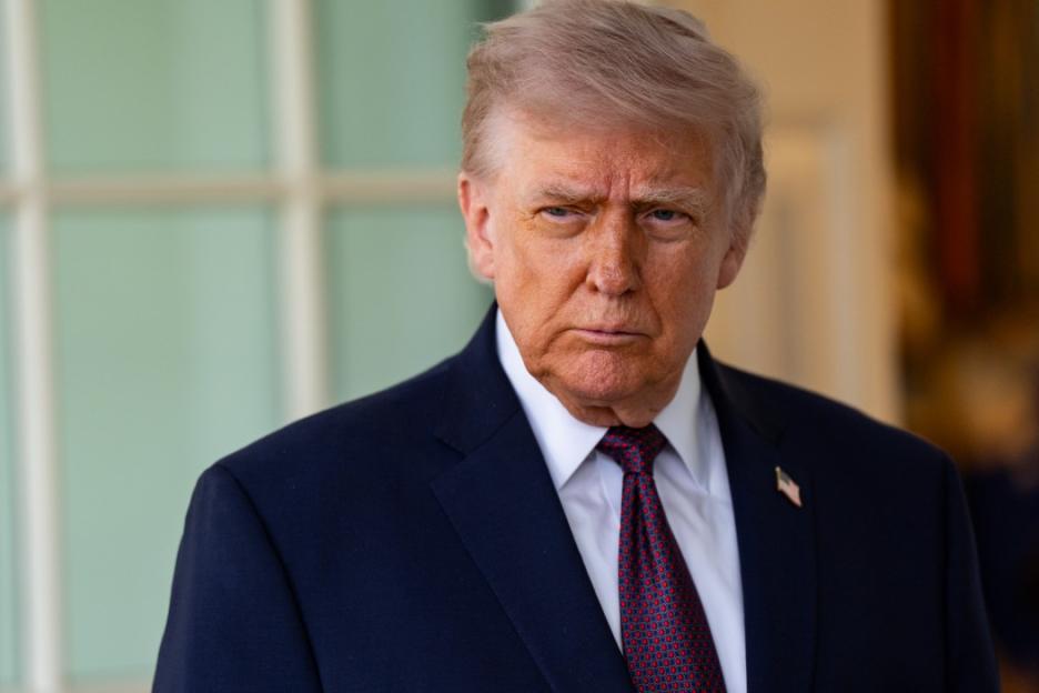 Donald Trump wearing a dark suit and a red patterned tie.