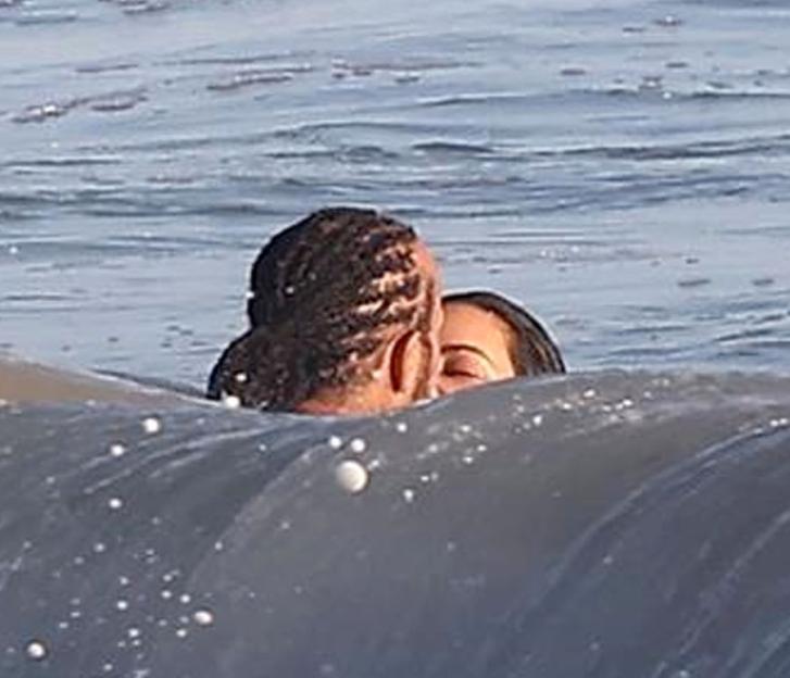 Kim Kardashian and Lewis Hamilton kissing in the ocean.