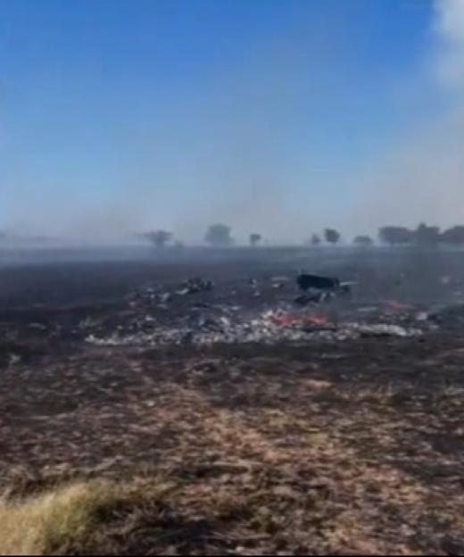 Debris and smoke in a scorched field after a plane crash.
