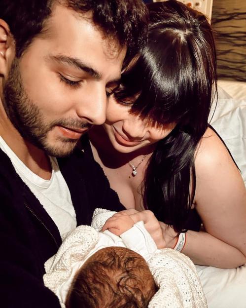 Daisy Lowe and her partner looking lovingly at their newborn baby.