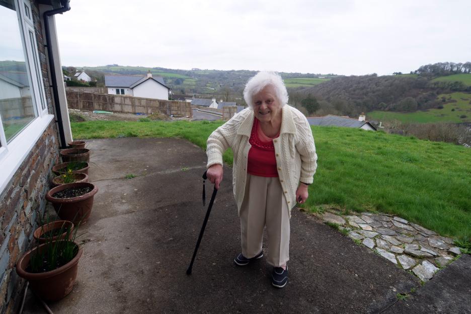 Pensioner Mary Jope with a cane, standing at the top of a steep dirt track on the development of new homes.