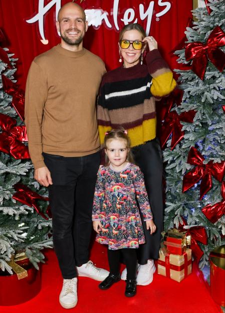 Kate Lawler and her family posing in front of a Hamleys sign and Christmas trees.