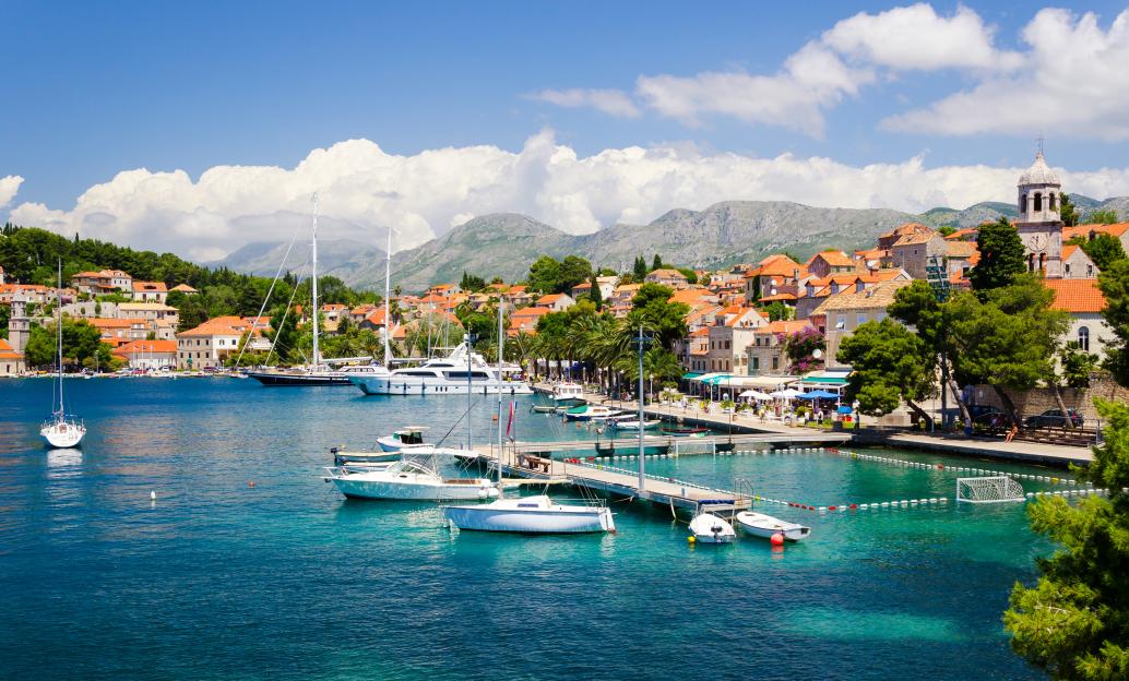 Cavtat town near Dubrovnik in Croatia, with boats in the harbor and mountains in the background.