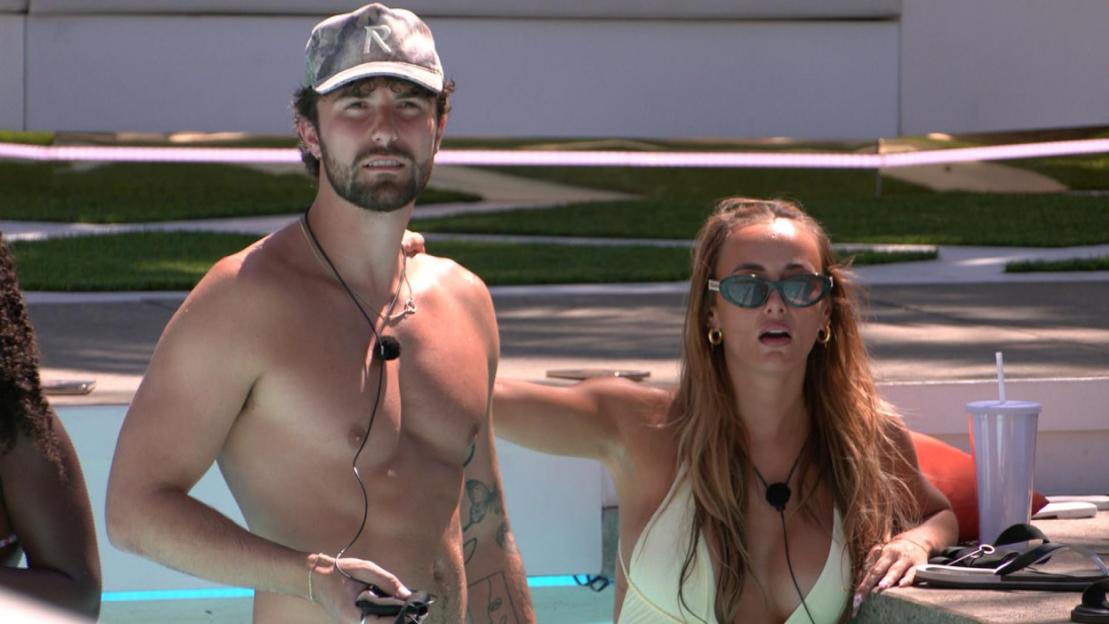 Man in a hat and woman in sunglasses in a swimming pool.