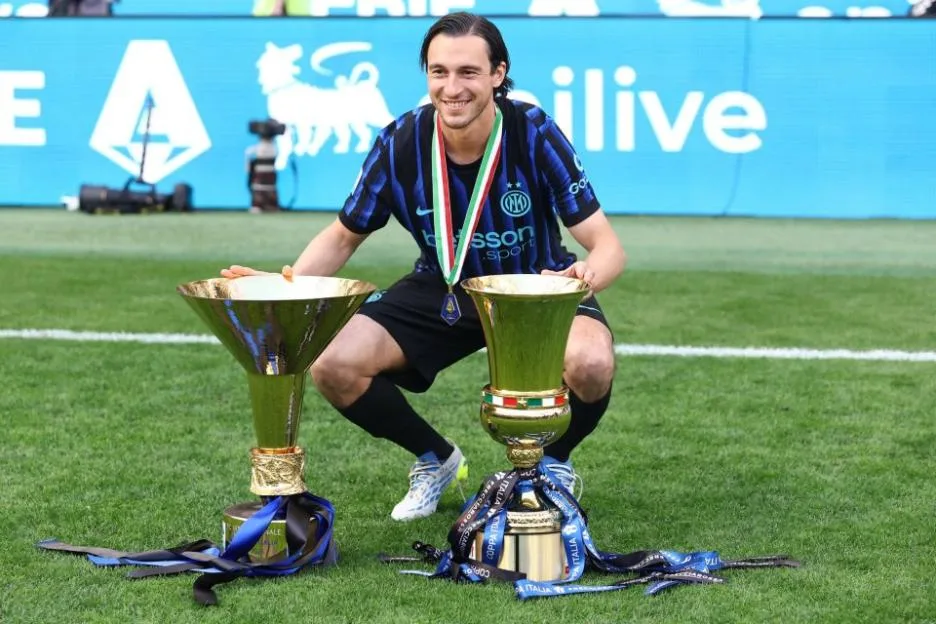 Matteo Darmian of FC Internazionale poses with two trophies on the pitch.