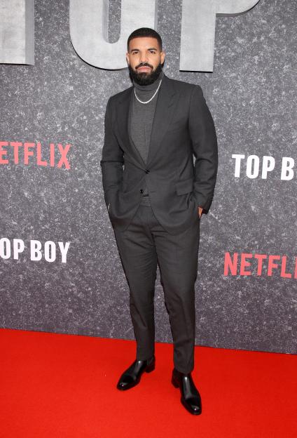 Drake on the red carpet, wearing a dark gray suit and turtleneck.