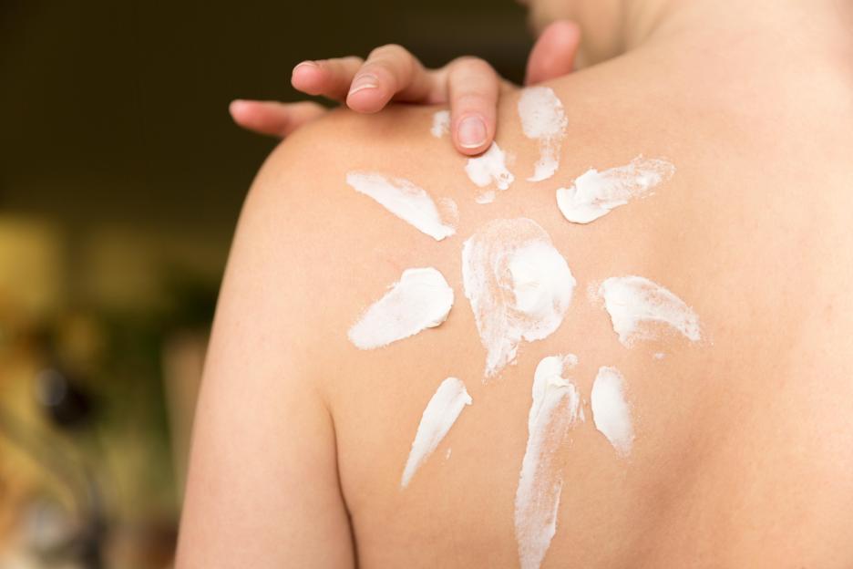 Person applying sunscreen in the shape of a sun.