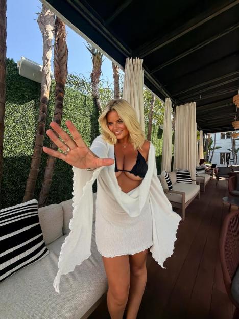 Woman in a bikini top and white cover-up extending her hand towards the viewer.