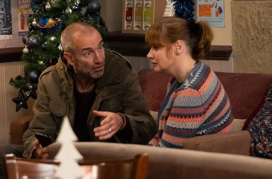 Sam Dingle and Kim Tate talking indoors, with a Christmas tree in the background.