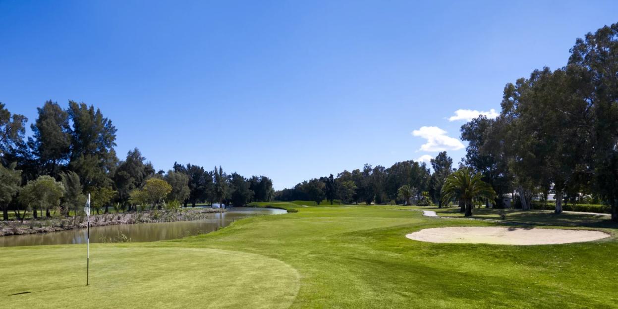 Penina Golf Resort with a golf course, flag, sand trap, and water feature.