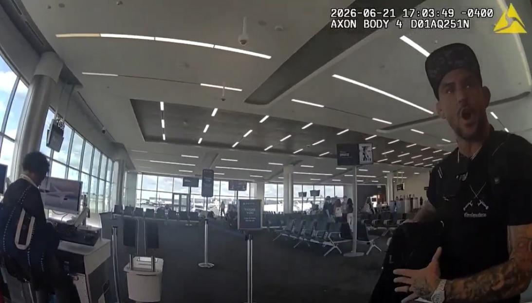 Former UFC star Dustin Poirier speaking to a police officer in an airport.