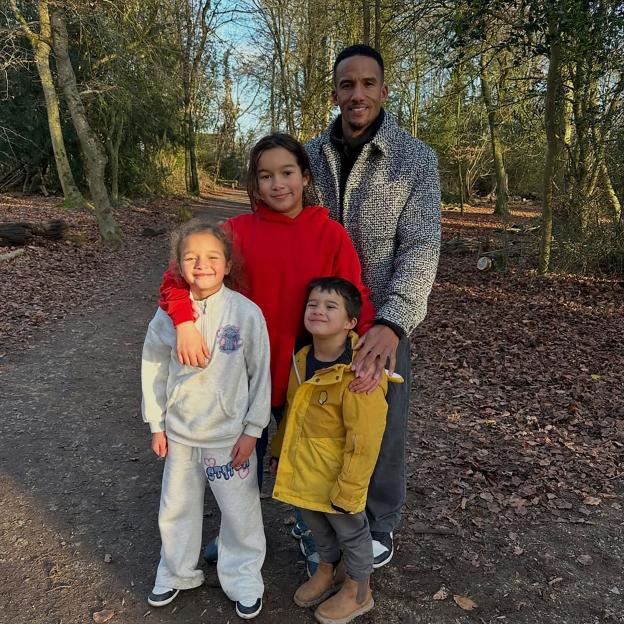 Scott Sinclair posing with his three children in a forest.