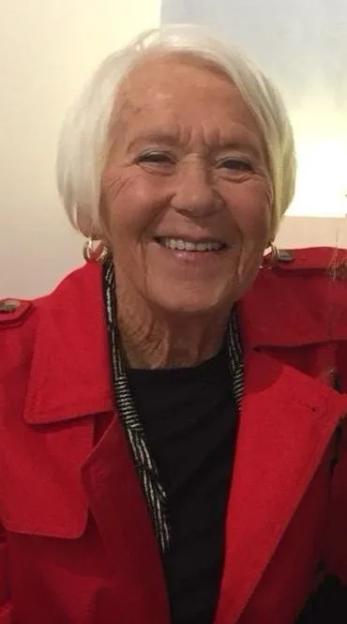 Gloria Stephenson, an elderly woman with white hair and a red coat, smiling.