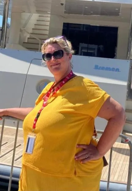 Woman in sunglasses posing in front of a yacht.