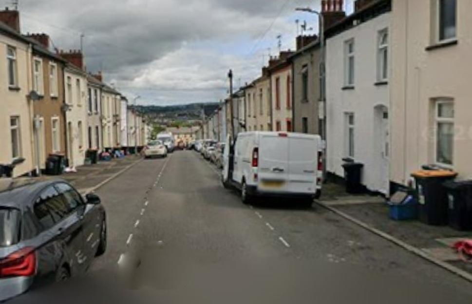 A street lined with residential houses and parked cars.