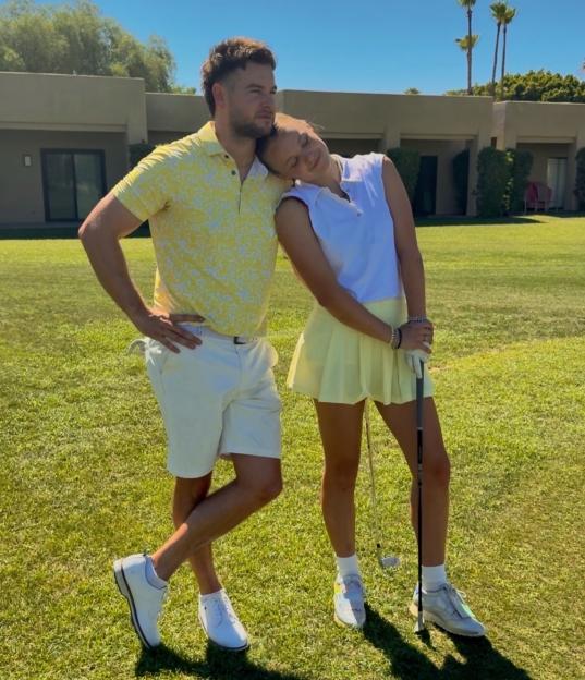 Chris Hughes and JoJo Siwa on a golf course, Siwa resting her head on Hughes' shoulder.