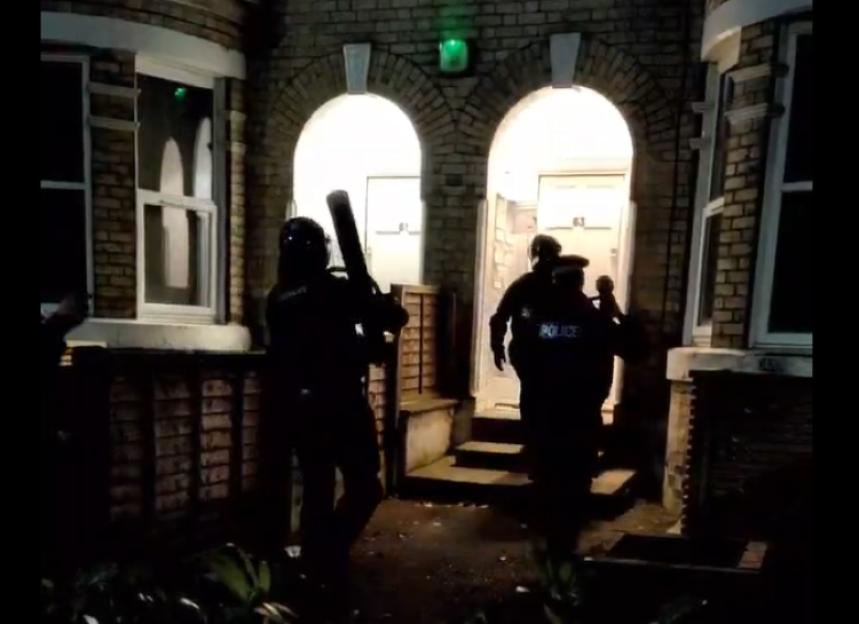 Police officers conducting a raid on a building at night.