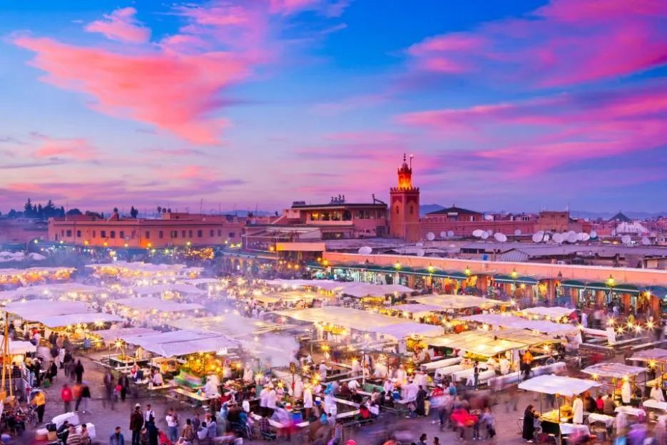 Vibrant sunset over the bustling Djemaa el-Fna square and market in Marrakesh.
