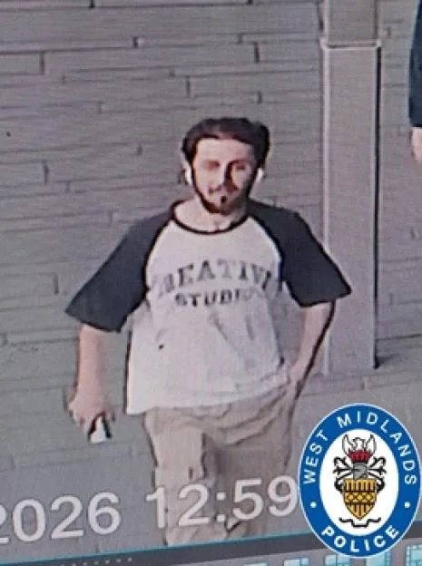 CCTV image of a young man with dark hair, a beard, and a mustache, wearing a t-shirt with dark sleeves and light-colored pants.