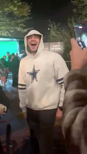 Tommy Fury wearing a white hoodie outdoors at night.