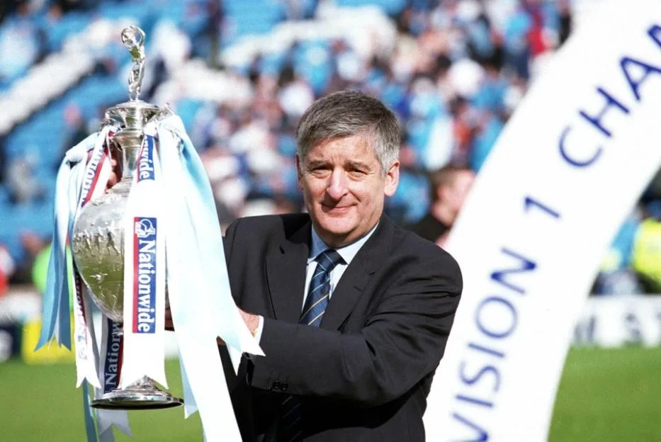 Manchester City Chairman David Bernstein celebrating with a trophy before a match.