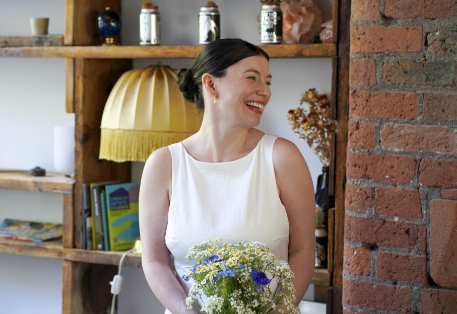 Amy Ward wearing her wedding dress and holding a bouquet of flowers.