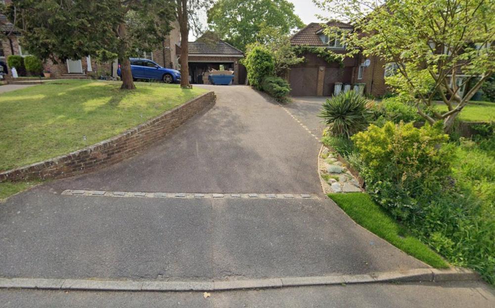 Two driveways separated by a brick wall and green space, leading to two houses.