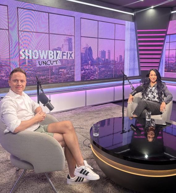 Two people on a set for "Showbiz Fix Uncut" podcast.