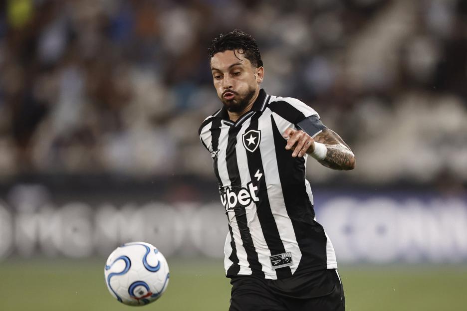 Soccer player wearing a black and white striped jersey, running towards the right side of the frame with a soccer ball.