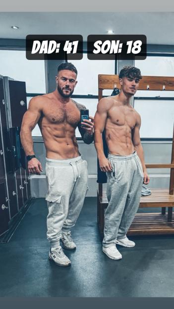 A 41-year-old man and his 18-year-old son, both shirtless and in sweatpants, pose in a locker room.