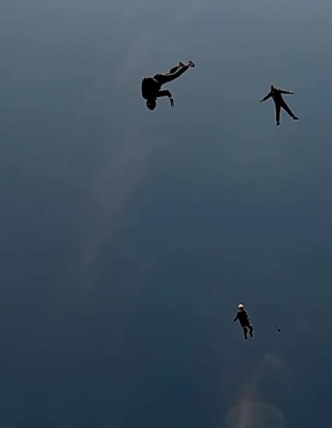 Three skydivers falling through the sky, one seemingly out of control.