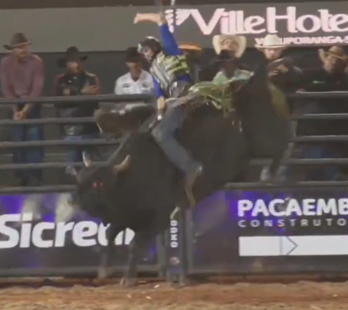 A bull rider mid-fall off a bucking bull during a rodeo event.