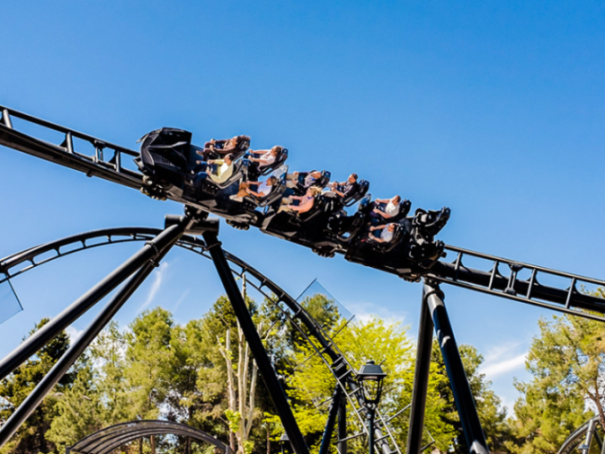 The Batman: Gotham City Escape roller coaster, with passengers, on its track above trees.