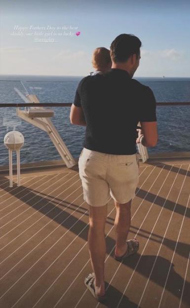 A man holding a baby and looking out at the ocean from a boat.