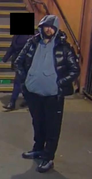 Man in a black puffer jacket, light blue hoodie, and dark pants.