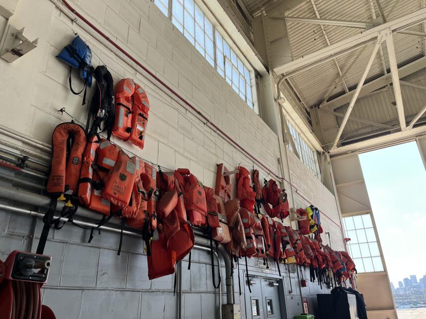 Life jackets hanging on a wall in a Coast Guard hanger.