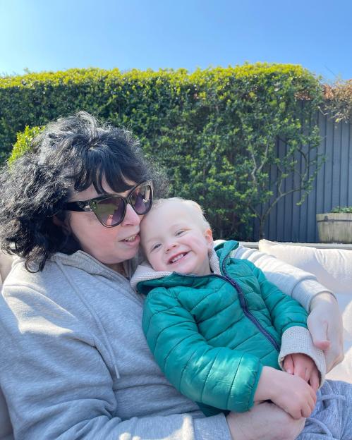 Adam Peaty's mum holding Adam Peaty's son George, who is smiling.