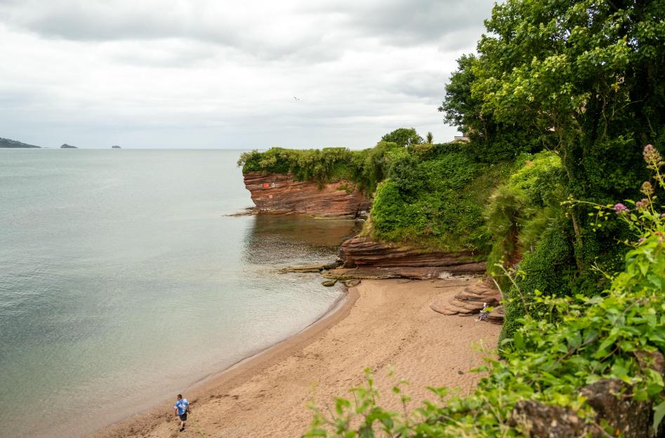Fairy Cove, a sandy beach and quiet bay in Paignton on the Devon coast, under a cloudy sky.