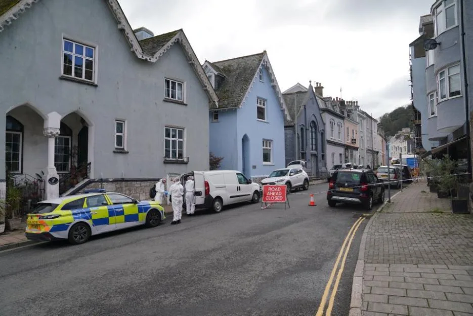 Police cars and forensic investigators in white suits outside a property on Newcomen Road in Dartmouth.