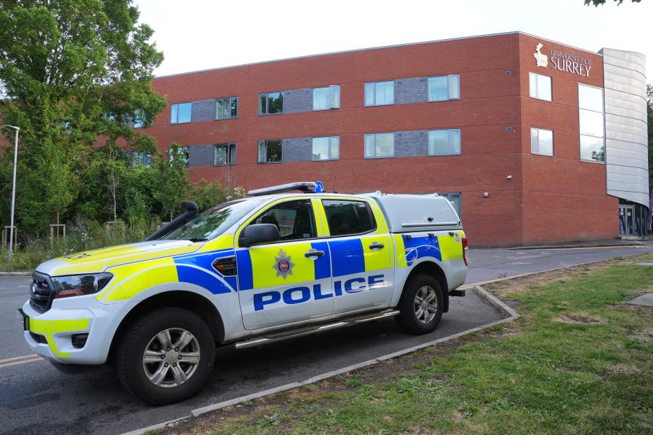A police car parked outside a building with "University of Surrey" on it.