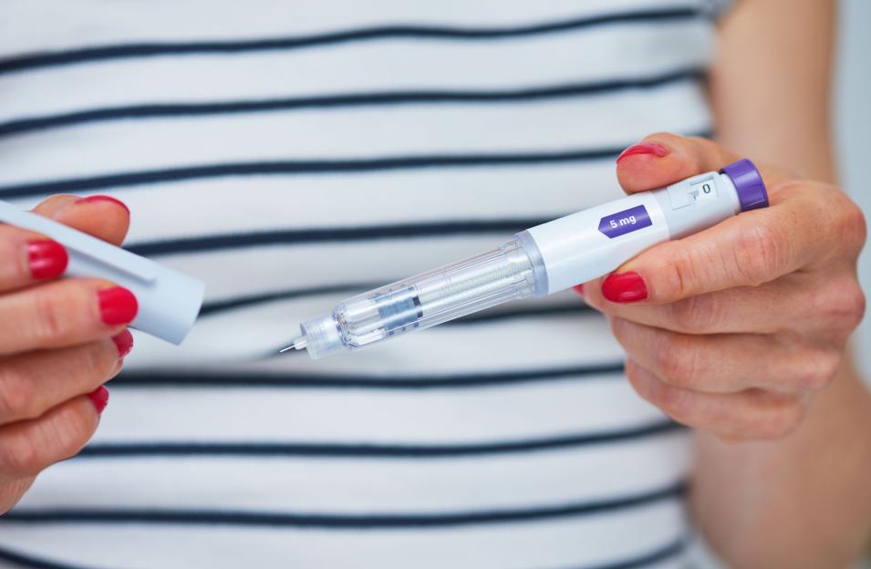 Woman using injection pen to administer weight loss drug -