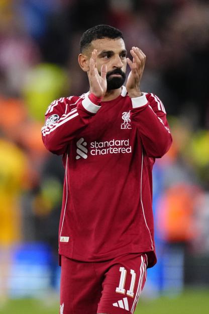 Liverpool FC player Mohamed Salah in a red jersey with number 11, clapping during the UEFA Champions League match.